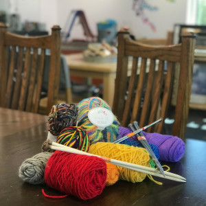 Different colored yarns sitting on a dark brown wood table